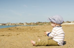 A toddler sitting on a beach.
