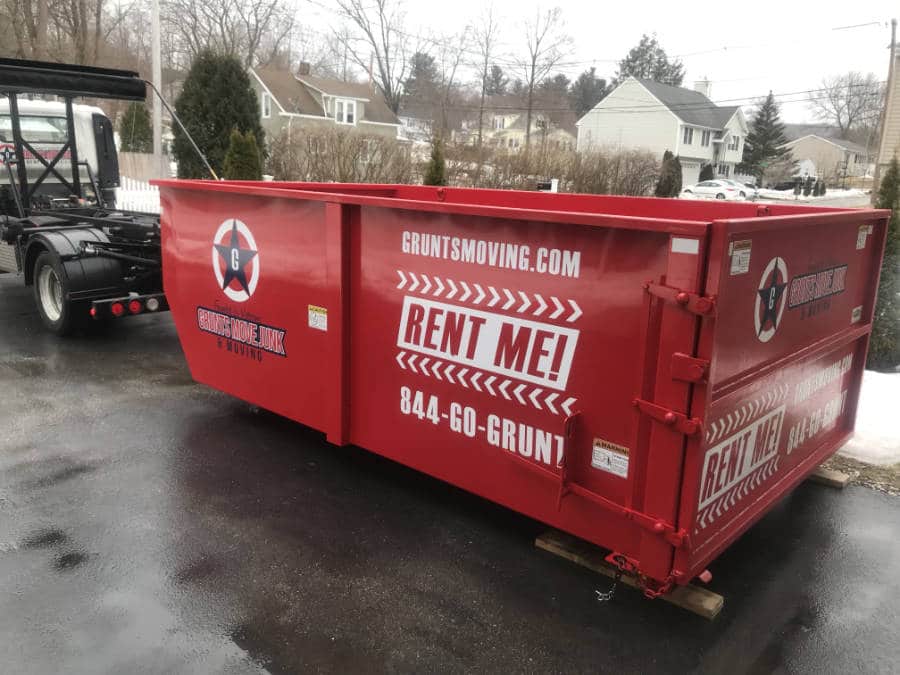 a dumpster rental in Worcester MA sitting in a residential driveway on a rainy day